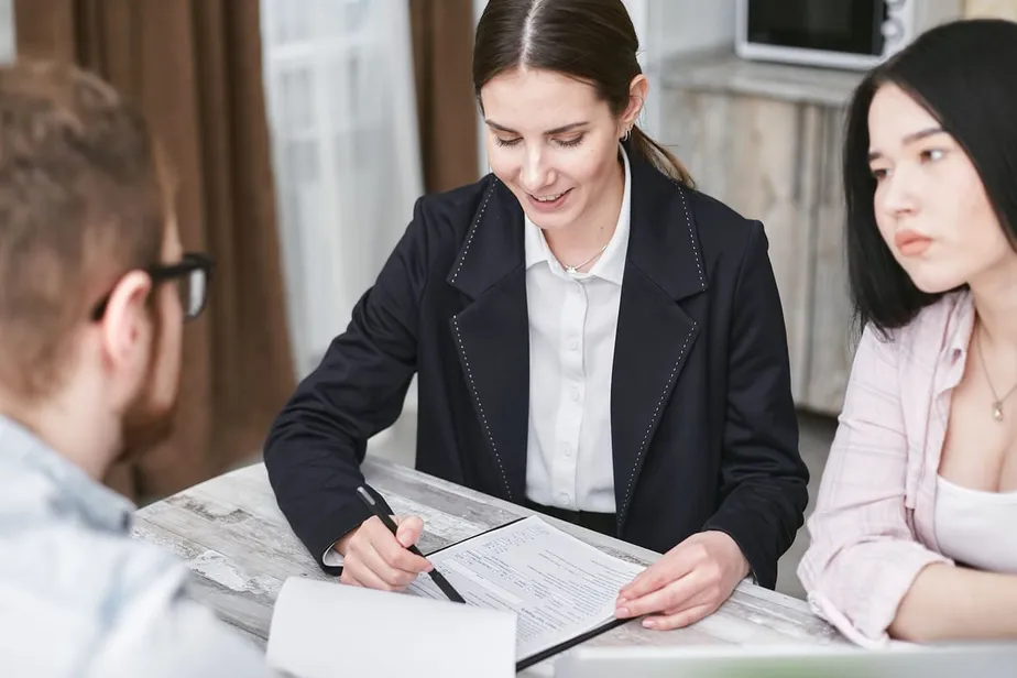 A consultant pointing out a section of an application form to two applicants across a desk